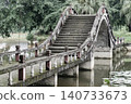 In Dazu Lotus Manor, a traditional stone bridge rises into a dramatic, steeply stepped arch. Framed by ornate balustrades, its flat walkway transitions seamlessly into a soaring vault over the calm 140733673
