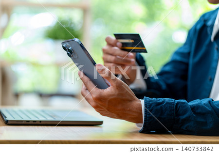 Side view close up right hand of business man hold black credit card and left hand hold mobile phone with concept of online payment with new normal and new trend of lifestyle. 140733842