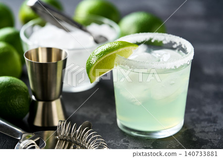 traditional cocktail Margarita served in salt rimmed tumbler over ice and garnished with a lime , selective focus. traditional cocktail Margarita served in salt rimmed tumbler over ice and garnished with a lime , selective focus. 140733881