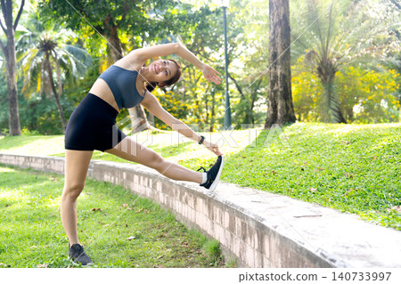 Asian woman relax after exercise in the garden with streching the body by lean on her right side and she look happiness. Asian woman relax after exercise in the garden with streching the body by lean on her right side and she look happiness. 140733997
