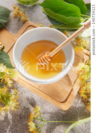 Linden honey in bowl with dipper and flowers Linden honey in bowl with dipper and flowers 140734121
