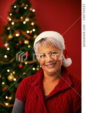 Christmas, smile and portrait of senior woman in studio for holiday celebration by tree isolated on a red background. Xmas, mature and face of happy female person in hat for festive party in Brazil 140734337