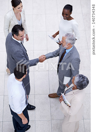 Team, handshake and happy business people with CEO for deal, collaboration or partnership agreement for diverse financial advisors. Top view, shaking hands and group in office meeting for acquisition Team, handshake and happy business people with CEO for deal, collaboration or partnership agreement for diverse financial advisors. Top view, shaking hands and group in office meeting for acquisition 140734348
