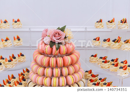 Colorful macarons, decorated cupcakes is set up on table for guests to enjoy at gathering. Colorful macarons, decorated cupcakes is set up on table for guests to enjoy at gathering. 140734351