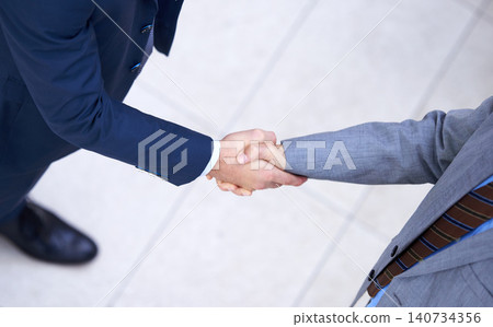 Top view, business people and handshake for deal, collaboration and b2b partnership agreement for consultant. Above, introduction and shaking hands for greeting, welcome and thank you in workplace Top view, business people and handshake for deal, collaboration and b2b partnership agreement for consultant. Above, introduction and shaking hands for greeting, welcome and thank you in workplace 140734356