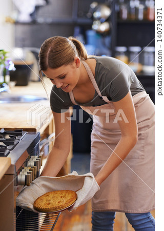 Bakery, oven and woman in kitchen cooking a pie as a chef at restaurant or hotel. Person, smile and baker preparing food in catering business with dinner or lunch dish and skill of baking pastry Bakery, oven and woman in kitchen cooking a pie as a chef at restaurant or hotel. Person, smile and baker preparing food in catering business with dinner or lunch dish and skill of baking pastry 140734371