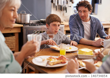 Father, family and eating breakfast at kitchen table for healthy nutrition in morning, orange juice or meal. Man, son and together in apartment for food wellbeing for weekend brunch, relaxing or kid Father, family and eating breakfast at kitchen table for healthy nutrition in morning, orange juice or meal. Man, son and together in apartment for food wellbeing for weekend brunch, relaxing or kid 140734854