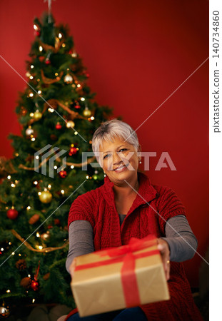 Christmas, senior and happy woman with gift in portrait at studio for holiday celebration by tree isolated on a red background. Xmas, giving and person with present or offer box for festive party 140734860