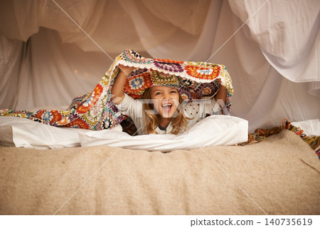Happy, blanket fort and portrait of child relaxing and playing hide and seek with quilt at home. Excited, smile and face of girl kid with positive, good and playful expression in bedroom at house. Happy, blanket fort and portrait of child relaxing and playing hide and seek with quilt at home. Excited, smile and face of girl kid with positive, good and playful expression in bedroom at house. 140735619