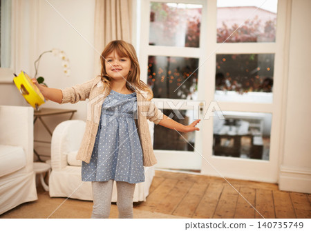 Little, girl and dance with portrait in living room for fun, entertainment and game with musical instrument. Kid, home and tambourine for sound or music to move, freedom and childhood with happiness. Little, girl and dance with portrait in living room for fun, entertainment and game with musical instrument. Kid, home and tambourine for sound or music to move, freedom and childhood with happiness. 140735749
