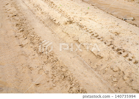 Traction tracks on a sandy country road. Deep tread marks from construction equipment or a heavy loader Traction tracks on a sandy country road. Deep tread marks from construction equipment or a heavy loader 140735994