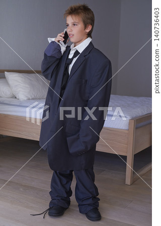 Pretend, kid and phone call with boy in suit, smartphone or business for dream job and aspiration with dress up. Thinking, happy in clothes on career day, talk on communication technology in costume 140736403