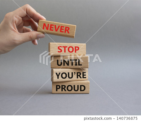 Never Stop symbol. Wooden blocks with words Never Stop Until You are Proud. Businessman hand. Beautiful grey background. Business and Never Stop concept. Copy space Never Stop symbol. Wooden blocks with words Never Stop Until You are Proud. Businessman hand. Beautiful grey background. Business and Never Stop concept. Copy space 140736875