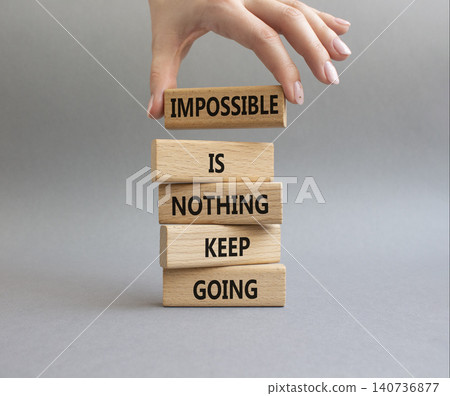 Keep Going symbol. Wooden blocks with words Impossible is Nothing Keep Going. Businessman hand. Beautiful grey background. Business and Keep Going concept. Copy space Keep Going symbol. Wooden blocks with words Impossible is Nothing Keep Going. Businessman hand. Beautiful grey background. Business and Keep Going concept. Copy space 140736877