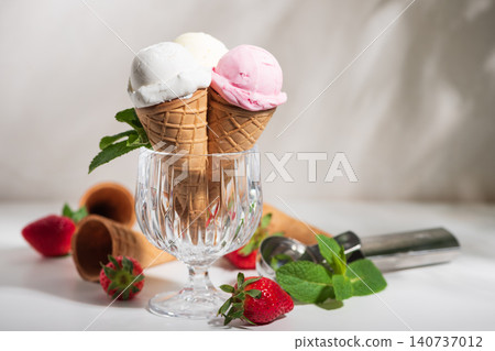 Ice cream scoops in waffle cones with strawberries and mint Ice cream scoops in waffle cones with strawberries and mint 140737012