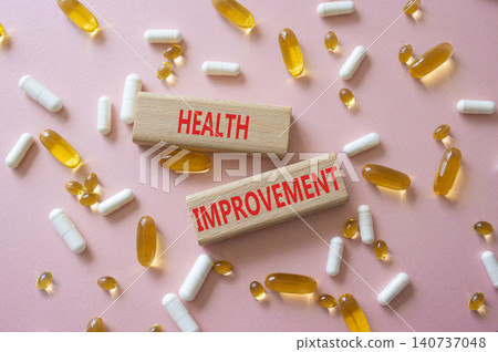 Health improvement symbol. Concept word Health improvement on wooden blocks. Beautiful pink background with pills. Medicine and Health improvement. Copy space Health improvement symbol. Concept word Health improvement on wooden blocks. Beautiful pink background with pills. Medicine and Health improvement. Copy space 140737048