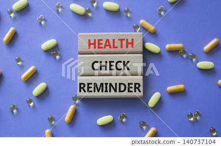 Health check reminder symbol. Concept words Health check reminder on wooden blocks. Beautiful purple background with pills. Healthcare and Health check reminder concept. Copy space. 140737104