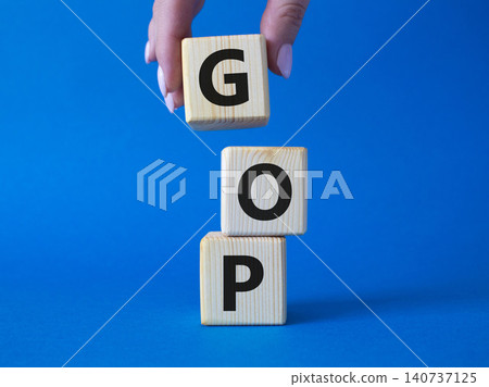GOP - Gross Operating Profit symbol. Concept word GOP on wooden cubes. Businessman hand. Beautiful blue background. Business and GOP concept. Copy space. GOP - Gross Operating Profit symbol. Concept word GOP on wooden cubes. Businessman hand. Beautiful blue background. Business and GOP concept. Copy space. 140737125