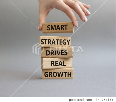 Growth symbol. Wooden blocks with words Smart strategy drives real growth. Businessman hand. Beautiful grey background. Business and Growth concept. Copy space Growth symbol. Wooden blocks with words Smart strategy drives real growth. Businessman hand. Beautiful grey background. Business and Growth concept. Copy space 140737133