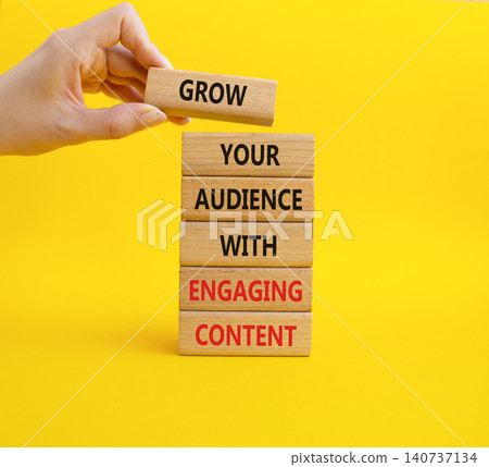 Grow your audience with engaging content symbol. Concept words grow your audience with engaging content on wooden blocks. Businessman hand. Beautiful yellow background. Business concept. Copy space. 140737134