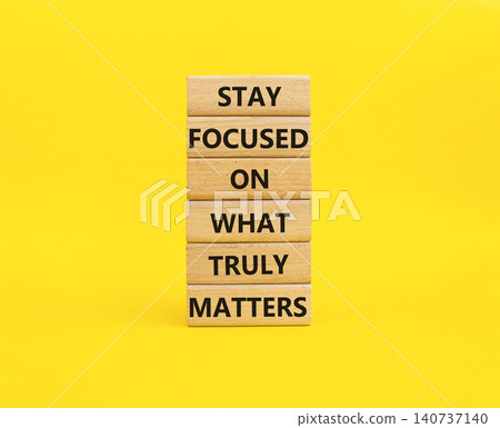 Stay focused on what truly matters symbol. Concept words stay focused on what truly matters on wooden blocks. Beautiful yellow background. Business concept. Copy space. 140737140