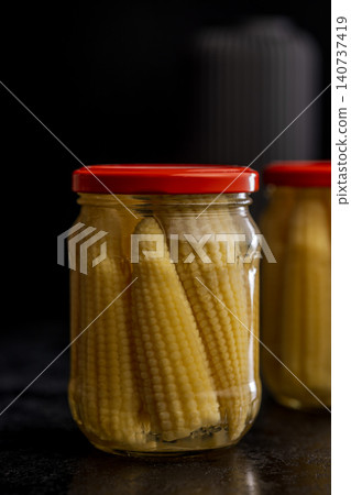 Jar of Baby Corn Preserved in Brine With Red Lid on Dark Background 140737419