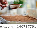 Hand dusts cocoa powder over tiramisu with metal sieve 140737791