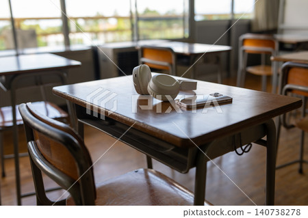A smartphone and earphones placed on a school desk. A smartphone and earphones placed on a school desk. 140738278