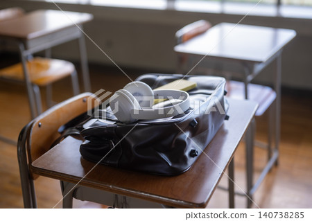 A bag and headphones placed on a classroom desk. 140738285