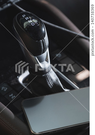 Car gear shift and mobile phone on console in a vehicle 140738369