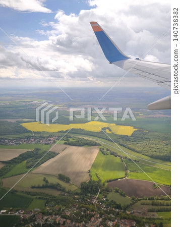 View from an airplane window of green and yellow fields below. View from an airplane window of green and yellow fields below. 140738382