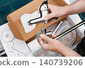 A man is doing repairs for a faucet replacement in a home renovation. The handyman and homeowner perform DIY repairs and plumbing, replacing an old faucet. 140739206
