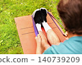 A man is stretching with a resistance band outdoors on a mat on the grass. This fitness workout and exercise routine improves health. 140739209
