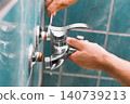 A man is doing repairs during a home renovation. This handyman and homeowner handles DIY repairs and plumbing, replacing an old faucet for a complete faucet replacement. 140739213