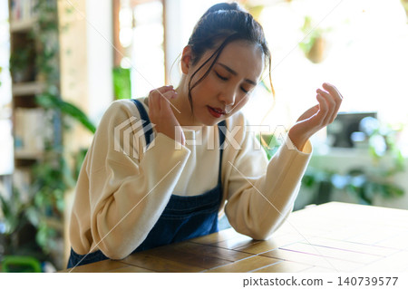 A young woman is sitting at her desk, racking her brain in worry. A young woman is sitting at her desk, racking her brain in worry. 140739577