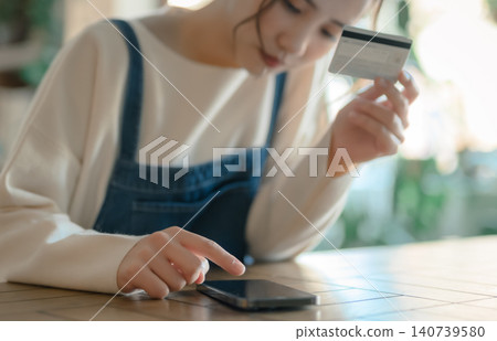 A woman performing a card payment operation in her hand. A woman performing a card payment operation in her hand. 140739580