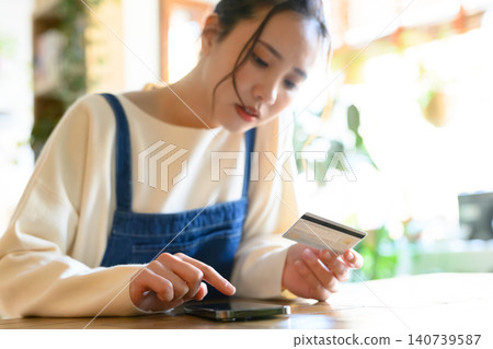 年輕女性使用智慧型手機支付購物 140739587