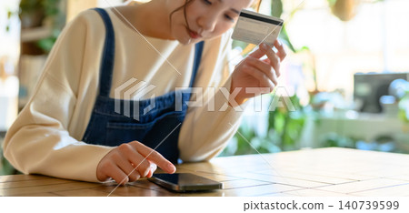 A young woman paying with her smartphone and card. 140739599