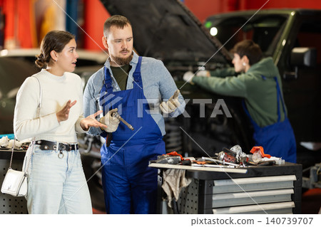 Woman talking to mechanic about car repair process Woman talking to mechanic about car repair process 140739707