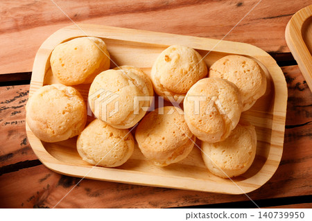 Traditional Brazilian cheese bread on a rustic wooden tray on a wooden table Traditional Brazilian cheese bread on a rustic wooden tray on a wooden table 140739950