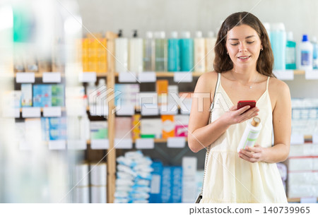 Girl scan barcode on shampoo in pharmacy Girl scan barcode on shampoo in pharmacy 140739965