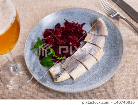On round blue plate - lightly salted herring fillet cut into pieces with stewed beets On round blue plate - lightly salted herring fillet cut into pieces with stewed beets 140740036