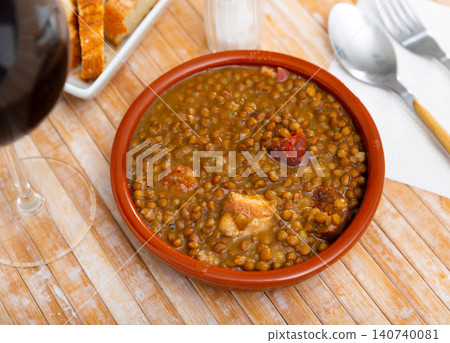 Stewed lentils with meat, chorizo and vegetables in clay cazuela 140740081