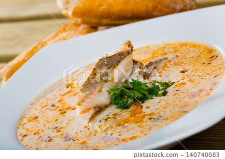 Tasty soup with white fish pollock and greens at white plate Tasty soup with white fish pollock and greens at white plate 140740083