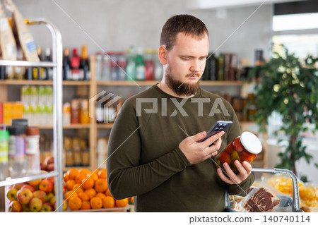 Man scanning barcode on pickled tomatoes Man scanning barcode on pickled tomatoes 140740114