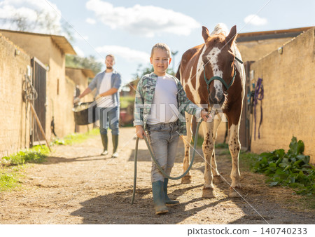 Boy leads horse by leash to feeding Boy leads horse by leash to feeding 140740233