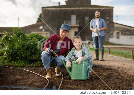 Young woman with boy planting seeds in field Young woman with boy planting seeds in field 140740234