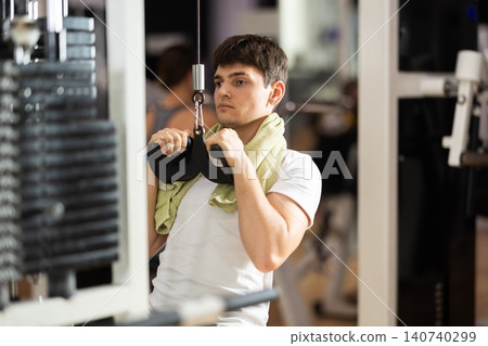 Guy pulling the handle towards himself in the machine Guy pulling the handle towards himself in the machine 140740299