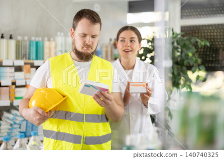 Laboring man builder buys pills at pharmacy, consulting with girl pharmacist Laboring man builder buys pills at pharmacy, consulting with girl pharmacist 140740325