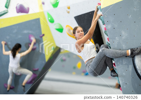 Young woman practicing rock climbing on climbing wall Young woman practicing rock climbing on climbing wall 140740326